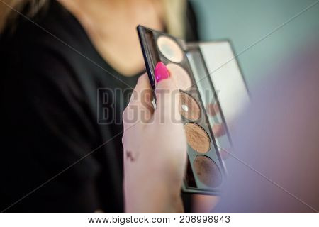 Cosmetic beauty procedures and makeover concept. Woman holds makeup professional palette. Make-up applying