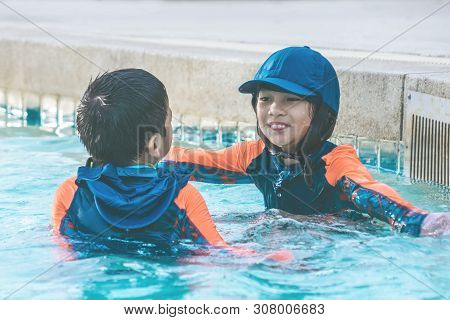 Two Asian Siblings In Playing Together In Water Aqua Park Pool.