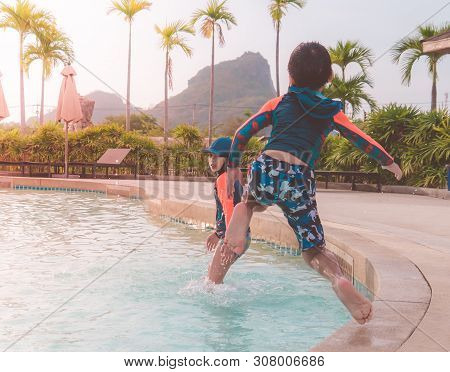 Two Asian Siblings In Jumping Down In Water Aqua Park Pool.