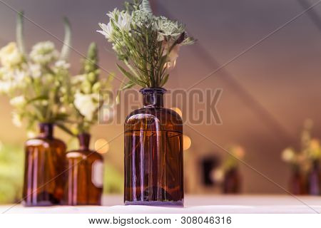 Image Of Modern Wedding Decoration With Flowers In Brown Bottels And Blurry Lights In The Background