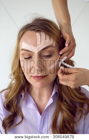 Beautician Aesthetician Glues Kinesio Tape On The Face