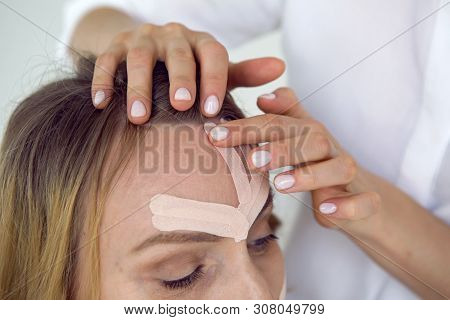 Beautician Aesthetician Glues Kinesio Tape On The Face