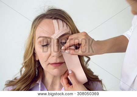 Beautician Aesthetician Glues Kinesio Tape On The Face