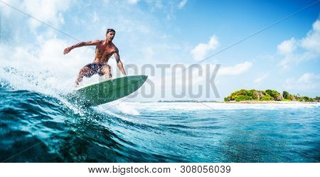 HIMMAFUSHI / MALDIVES - MARCH 10, 2019: Panorama of the young surfer with lean muscular body riding the tropical wave