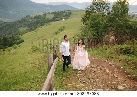 Beautiful Young Wedding Couple Standing On The Green Slope, Hill. Groom And Bride In Carpathian Moun