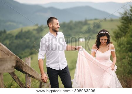 Beautiful Young Wedding Couple Standing On The Green Slope, Hill. Groom And Bride In Carpathian Moun