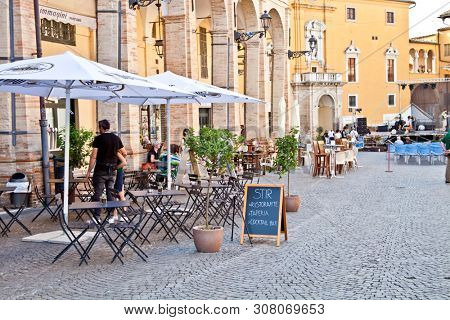 Fermo, Italy - June 23, 2019: People enjoying summer day and food at outdoor restaurant and resting, Piazza del Popolo, Fermo, Italy