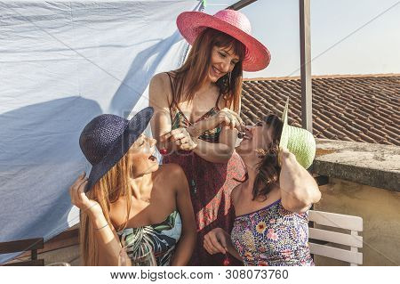 Group Of Female Friends Having Fun While Eating Cherries On The Rooftops