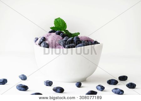 Ice-cream Decorated With Fresh Berries Of A Honeysuckle And Green Leaves On White Background. Close-
