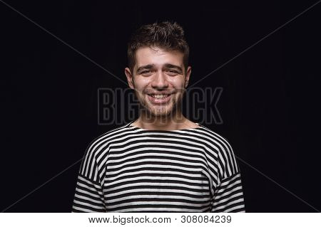Close Up Portrait Of Young Man Isolated On Black Studio Background. Photoshot Of Real Emotions Of Ma