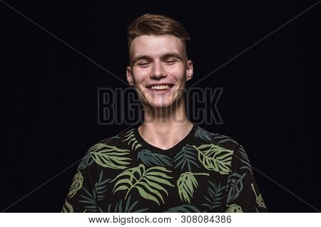 Close Up Portrait Of Young Man Isolated On Black Studio Background. Photoshot Of Real Emotions Of Ma