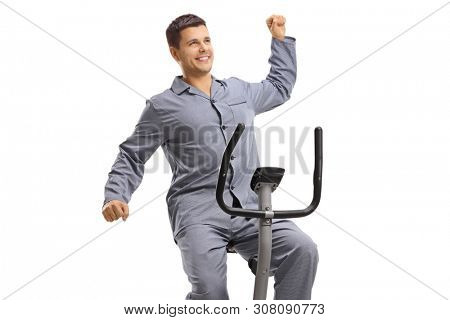 Young guy in pajams stretching on an exercise bike isolated on white background