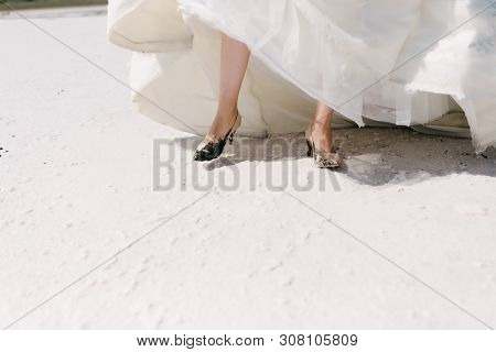 The Legs Of The Bride In A Wedding Dress In Shoes Close Op