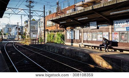 Kyoto, Japan - November 20, 2018: Tourist Sit On Bench Waiting Train Of Keifuku Electric Railroad Ki