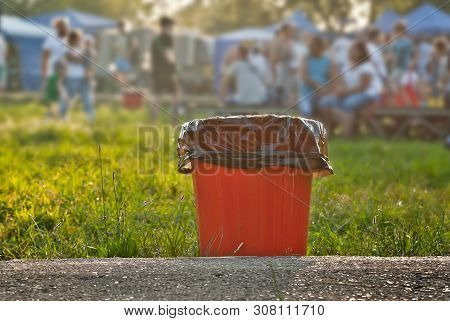 Red Litter On Green Grass. Garbage In The Nature After The Concert.