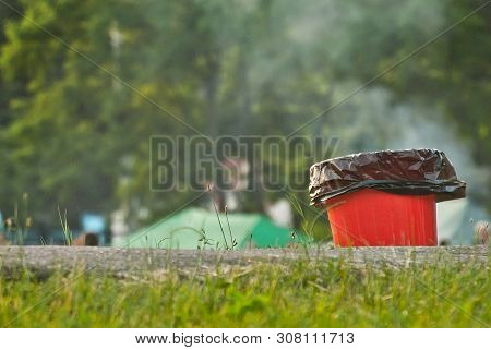 Red Litter On Green Grass. Garbage In The Nature After The Concert.