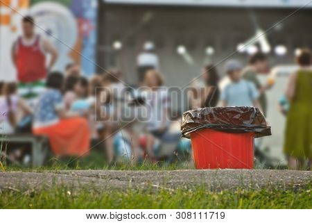 Red Litter On Green Grass. Garbage In The Nature After The Concert.