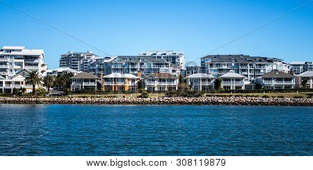 Harbourside Condominium Apartments Behind Free Standing Houses With Grass Frontage, Stone Retaining 