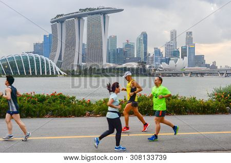 Singapore - February 16, 2017: People Running By The Embankment Of Singapore River In Front Of Singa