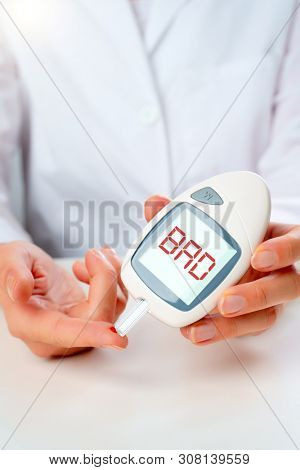 Photo of hand man with glucometer with bro inscription in studio
