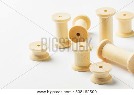 Variety Of Wooden Thread Spools Of Different Sizes Scattered On White Background. Sewing Crafts Hobb