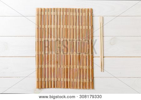 Two Sushi Chopsticks With Empty Bamboo Mat Or Wood Plate On Wooden Background Top View With Copy Sta