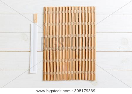 Two Sushi Chopsticks With Empty Bamboo Mat Or Wood Plate On Wooden Background Top View With Copy Sta