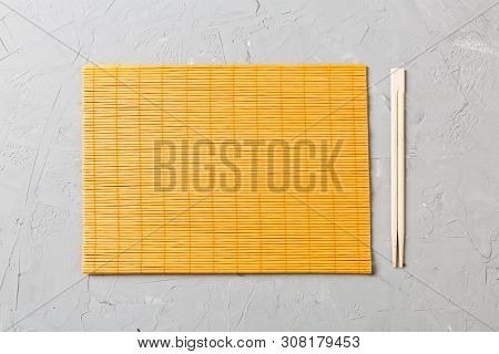 Two Sushi Chopsticks With Empty Bamboo Mat Or Wood Plate On Stone Background Top View With Copy Stac
