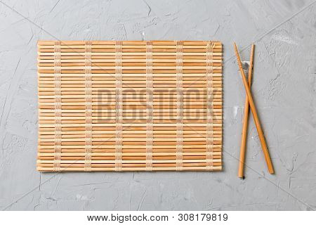Two Sushi Chopsticks With Empty Bamboo Mat Or Wood Plate On Stone Background Top View With Copy Stac