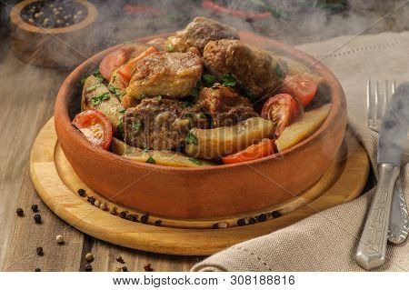 The Traditional Pork And Potato Dish Of Georgian Cuisine On Earthenware Ketsi. Hot Steam Dish. Ojahu