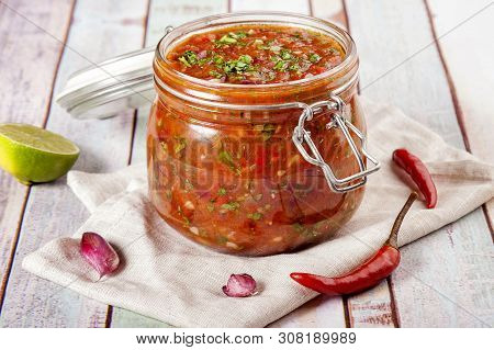 Tomato Salsa In A Glass Jar. Homemade Spicy Tomato Sauce With Chilli, Garlic And Lime. Close Up And 