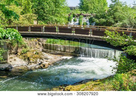 A Walking Bridge Spans The Deschutes River At Tumwater Falls In Washington State.