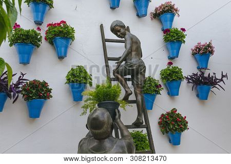 Cordoba, Spain - April 14th, 2019: Sculpture Made Of Bronze With A Child And His Grandfather Caring 