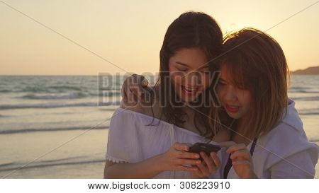 Young Asian Lesbian Couple Using Smart Phone Near Beach. Beautiful Women Lgbt Couple Happy Relax Enj