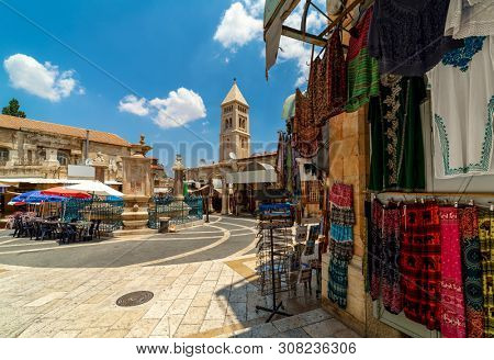 Small square with fountain among gift shops as belfry on background in Muristan - famous historic complex of streets in Christian Quarter of Old City of Jerusalem, Israel.