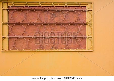 Yellow Wall With Trellised Battened Window. Round Elements Of Rack Bar. Industrial Construction Clos
