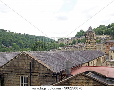 A View Of The Steep Hillside Streets In Hebden Bridge Between Summer Trees With The Tower Of The His