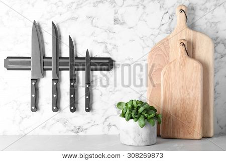 Magnetic Holder With Set Of Knives On Marble Wall In Kitchen