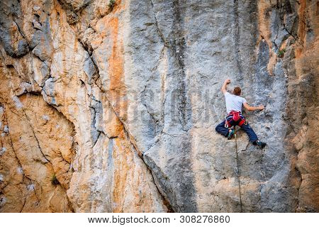 Athletic Man Climbs A Rock, 7c Category Route In The Forest With Rope. Sport Climbing In Crimea, Lea