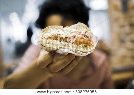 Person Holding Half A Lox Bagel With Cream Cheese, Onions, Capers, And Tomato.
