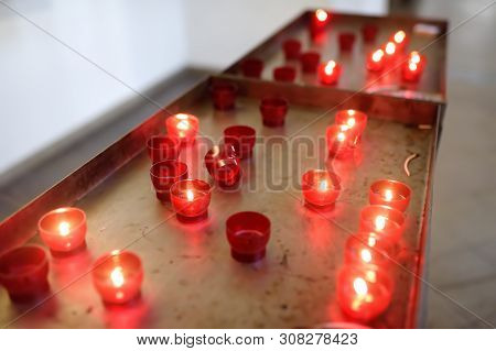 Close-up Photo Of Church Candles In Red Transparent Chandeliers In Church.