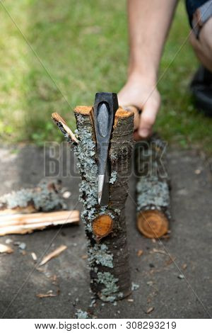 A Man With An Ax Chopping Logs. Ax In Wood Chock