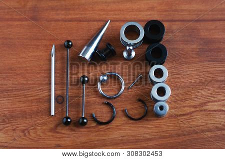 Jewelry Piercing Set. Piercing Accessories On Wooden Background. Stretching For Ear Tunnels , A Cath