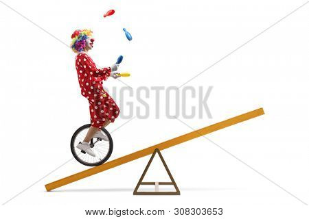 Full length shot of a clown riding a unicycle on a beam and juggling isolated on white background