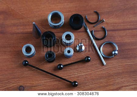 Jewelry Piercing Set. Piercing Accessories On Wooden Background. Stretching For Ear Tunnels , A Cath