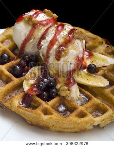 Gofre - Belgian Homemade Waffles With Ice Cream, Bananas And Nuts On A White Plate