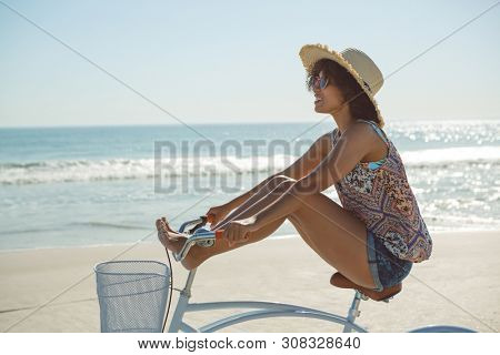 Side view of beautiful Caucasian woman riding a bicycle with her legs on handlebar at beach