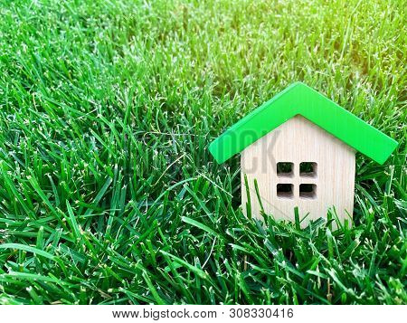 Miniature Wooden House On Green Grass. Real Estate Concept. Eco-friendly And Energy Efficient House.