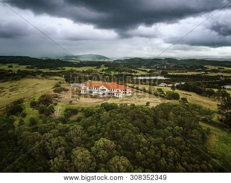 Storm Clouds Loom Heavy Over An Abandoned Mansion That Now Sits Derelect In Rural Countryside