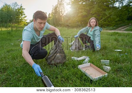 Friends Crouching With Bag Picking Up Trash Doing Plogging.plogging Concept. Boy And Girl Picking Up